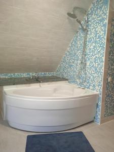 y baño con bañera blanca y azulejos azules. en Апартаменти " З ЛЮБОВ'Ю ", en Novyy Kropivnik