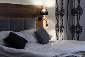 a bed with black and white pillows on it at Willa Nosalowa Dolina in Zakopane