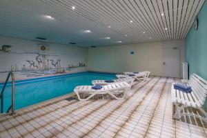 ein Zimmer mit weißen Stühlen und einem Pool in der Unterkunft Ferienwohnanlage-Oberaudorf 1 Zimmer App E 8 mit Hallenbad und Sauna in Oberaudorf