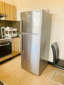 a stainless steel refrigerator in a kitchen with a chair at Penthouse Apartment Masaki in Dar es Salaam