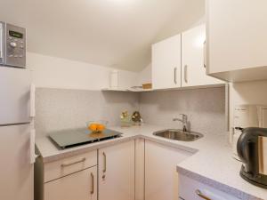 uma cozinha com armários brancos e um lavatório em Ferienwohnanlage Oberaudorf E7 mit 2 Schlafzimmer und Hallenbad em Oberaudorf
