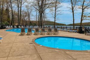 a swimming pool with lounge chairs and a lake at Downhill Delight in Lake Harmony