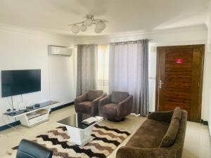 a living room with a couch and two chairs and a tv at Penthouse Apartment Masaki in Dar es Salaam