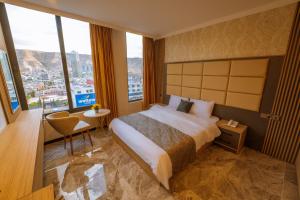 um quarto de hotel com uma cama e janelas grandes em Sarok Hotel em Dohuk