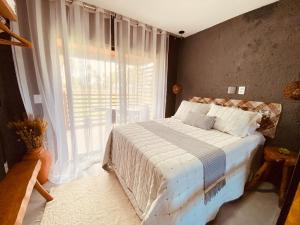 a bedroom with a bed and a large window at Flat Villas Manatee Rota Ecológica dos Milagres in Pôrto de Pedras