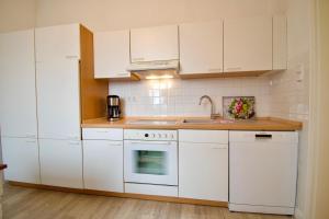 una cocina blanca con armarios blancos y fregadero en Villa Wilhelma Strandallee 146 Villa Wilhelma Apartment 18, en Timmendorfer Strand