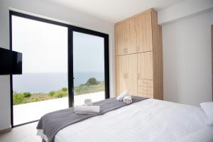 1 dormitorio con 1 cama grande y ventana grande en Sea Whisper with Private Pool & Panoramic Sea view, en Plateies