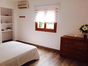 um quarto com uma cama, uma janela e uma cómoda em SON BUSQUERET em Ses Covetes