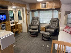 a living room with two chairs and a tv in a trailer at Betsie -35Ft RV Camper in Woods -Firepit & Hot Tub in Benzonia