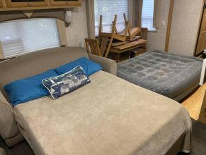 a living room with two beds and a chair at Betsie -35Ft RV Camper in Woods -Firepit & Hot Tub in Benzonia