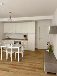 a kitchen with white cabinets and a table and chairs at Tati&Ele apartments in Sedico