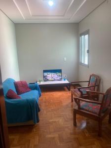 a living room with a blue couch and two chairs at Apartamento em Passo Fundo in Passo Fundo
