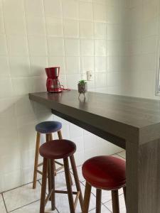 a kitchen with two stools and a counter with a table at Apartamento em Passo Fundo in Passo Fundo