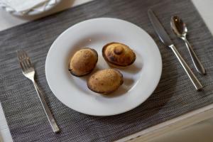 a plate of food with three potatoes on a table at Masseria Corda Di Lana Hotel & Resort in Torre Lapillo