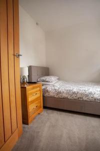 um quarto com uma cama e uma cómoda de madeira com uma mesa de cabeceira em Three Bedroom House, Driveway, Bracknell Centre em Bracknell