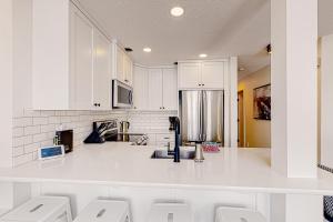 Una cocina con gabinetes blancos y una encimera blanca. en Ice and Cozy #116C, en Big White