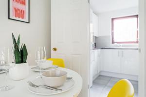 uma sala de jantar com uma mesa branca e cadeiras amarelas em The Merchants Gem - 2Bed & Free Parking em Glasgow