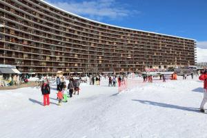 Un groupe de personnes dans la neige devant un grand bâtiment dans l'établissement Résidence Le Bois D'aurouze - Studio pour 2 Personnes 354, à Saint-Étienne-en-Dévoluy