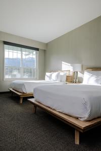 two large beds in a room with a window at Balcomo - A Ramada By Wyndham in Penticton