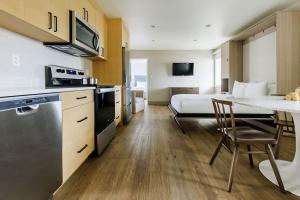a room with a bed and a kitchen with a table at Ramada by Wyndham Penticton Hotel & Suites in Penticton