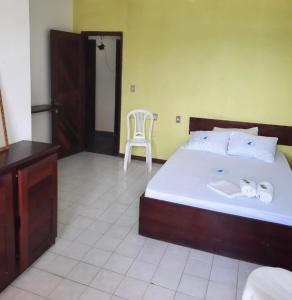 a bedroom with a large bed and a chair at Pousada Tubarão in Camaçari