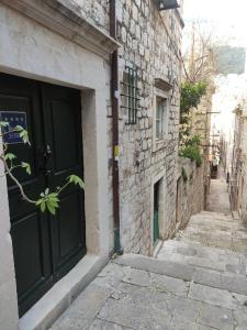 un vicolo con una porta nera su un edificio di pietra di Shee-Lu Suite 2 a Dubrovnik