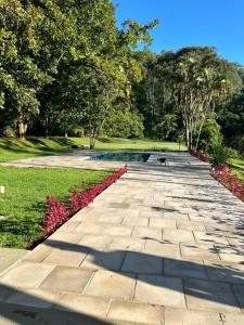 Una pasarela de piedra en un parque con flores rosas en Fazenda São Miguel en Monte Alegre do Sul