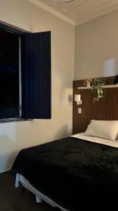 a bedroom with a black bed with a window at Fazenda São Miguel in Monte Alegre do Sul