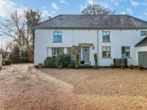 a white house with a gravel driveway at 4 bed in Okehampton 49511 in Sampford Courtenay