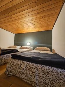 three beds in a room with a wooden ceiling at Rifugio Guglielmo e Giovanni Pelizzo in Montemaggiore