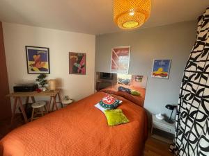a bedroom with a bed with an orange comforter at Splendide appartement 40m2 familial cabourg in Cabourg