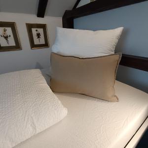 un letto con lenzuola bianche e un cuscino sopra di Privates Zimmer & Bad in Aalen/Unterkochen a Unterkochen
