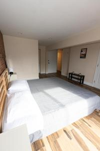 uma grande cama branca num quarto com pisos em madeira em Elegant & Spacious 3-Bed Space near NYC em Jersey City