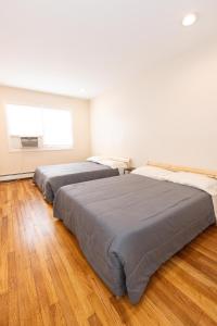 Duas camas num quarto com pisos de madeira em Elegant & Spacious 3-Bed Space near NYC em Jersey City