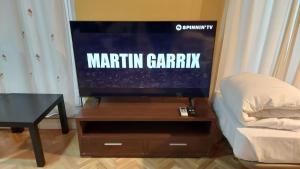 TV de pantalla plana en un soporte de madera con mesa en Apartamentos Sol Mayor, en Madrid