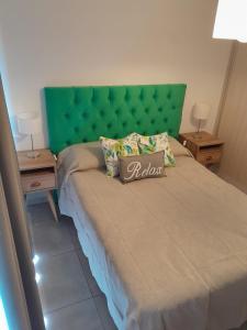 een bed met een groen hoofdeinde in een slaapkamer bij URBANO Dpto in Villa María
