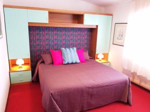 a bedroom with a large bed with pink pillows at Alla Posta Guest House in Garna dʼAlpago