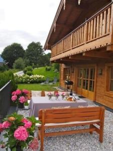 a wooden bench sitting in front of a house with a table at Nettes Ferienhaus in Gaisbichl mit Terrasse und Garten in Niedernsill