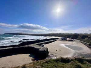 a view of a beach with a pier and the ocean at Modern Refurbished Church nr Butt of Lewis beaches in Port of Ness