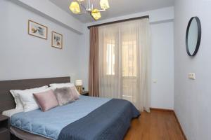 a bedroom with a bed with a blue blanket and a window at Apartment near Republic Square in Yerevan