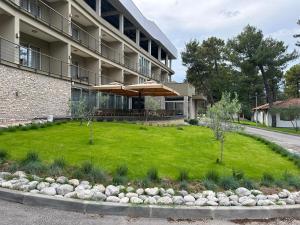 a lawn in front of a building with umbrellas at GRANDE CASA Hotel - Međugorje in Međugorje