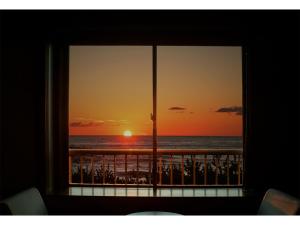 ein Fenster mit Blick auf den Strand bei Sonnenuntergang in der Unterkunft Taiheian - Vacation STAY 57423v in Sakai