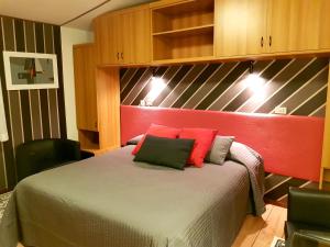 1 dormitorio con 1 cama con almohadas rojas y verdes en Alla Posta Guest House, en Garna dʼAlpago