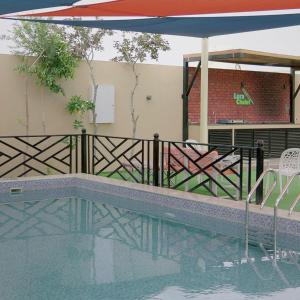 a swimming pool with a fence and an umbrella at Lura Chalet in Barka
