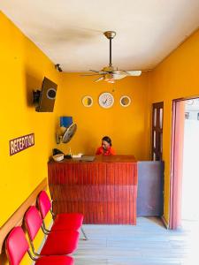 a man sitting at a bar in a restaurant with a clock at Constellation Hotel 3 in Dajabón