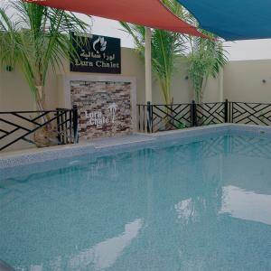a large swimming pool in a hotel with palm trees at Lura Chalet in Barka