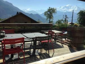 a group of tables and chairs on a deck with mountains at K'banalours in Sallanches