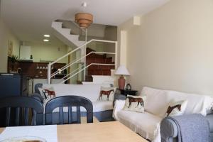 un soggiorno con divano, sedie e scala di Tu Casa Ecuestre a Villavieja del Lozoya