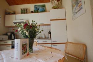 una cocina con una mesa con un libro y flores. en Schönes Ferienhaus in Rothhelmshausen mit Garten, Terrasse und Grill en Fritzlar