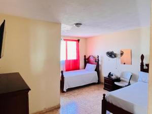 een slaapkamer met 2 bedden en een raam bij Constellation Hotel 3 in Dajabón